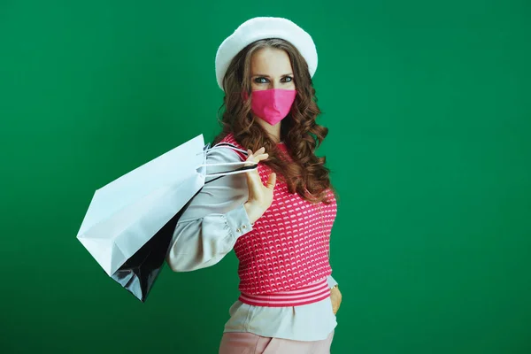 在大肠病毒大流行期间的生命 穿着粉色无袖无袖衬衫 戴着粉色医疗面具 头戴绿色购物袋的现代女性购物者的画像 — 图库照片