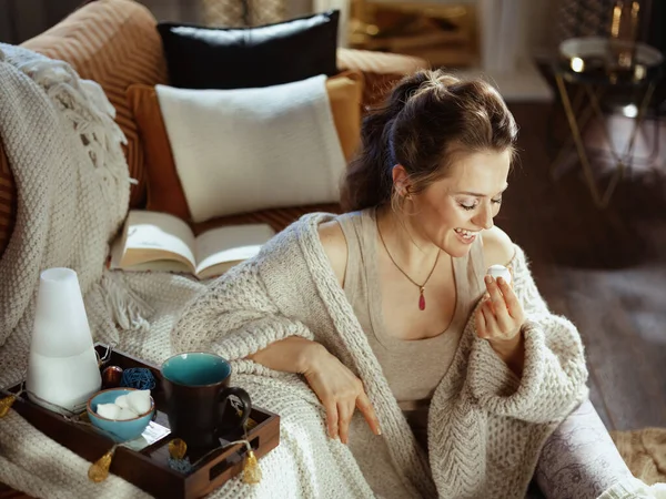 Glimlachende Moderne Vrouw Gebreid Gezellig Vest Met Boek Dienblad Aromalamp — Stockfoto