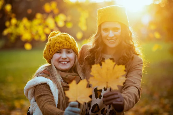 9月だ 秋には公園の外に黄色の葉を持つ黄色の帽子の幸せな若い母親と娘 — ストック写真