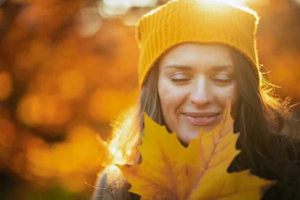 茶色のコートを着た若い女性と黄色の帽子秋に市公園の屋外で黄色の葉 — ストック写真