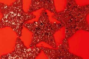 Kırmızı arka planda yıldız şekilli Noel oyuncaklarıyla yatıyordu.