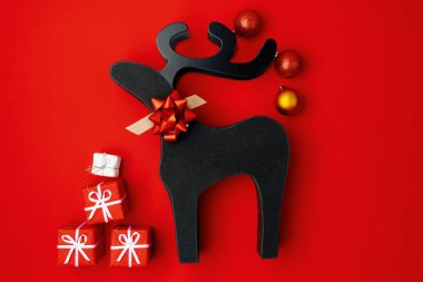 flat lay with christmas ball, christmas reindeer and present box on red background.