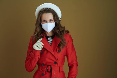 Covid-19 salgını sırasında hayat. Kırmızı ceketli şık orta yaşlı kadın kahverengi arka planda izole edilmiş..