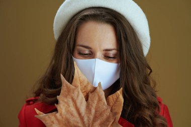 Merhaba sonbahar. Sarı sonbahar akçaağaç yaprağıyla bej arka planda kırmızı ceketli rüya gibi bir ev hanımı..