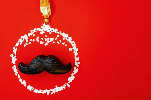 flat lay with christmas ball and mustache on red background.