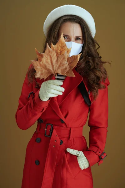 Covid 19大流行病期间的生活 黄秋枫叶 背景为褐色 身穿红色外套的年轻貌美女子 — 图库照片
