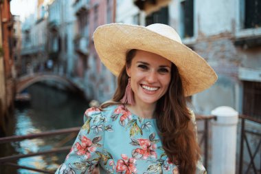 Gülümseyen orta yaşlı kadın portresi. Çiçekli elbiseli, şapkalı, Venedik, İtalya 'da gezintiye çıkmış..