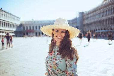 Venedik, İtalya 'da San Marco Meydanı' nda yürüyen şapkalı, çiçekli genç bir yolcu..