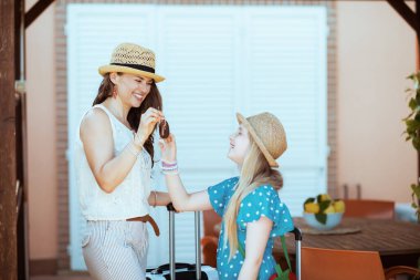 Modaya uygun anne ve çocuk gezginleri, otel odasının avlusunda ellerinde çanta ve anahtarlarla geziyorlar..