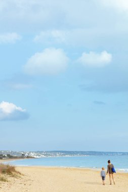 Plajlı manzara, bulutlar, yürüyen anne ve kız.