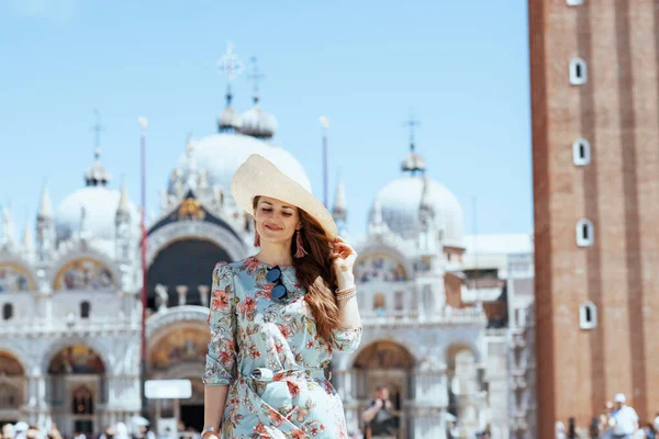 サングラスと帽子を持つ花のドレスで流行の女性を笑顔ヴェネツィア イタリアのサンマルコ広場での遠足 — ストック写真