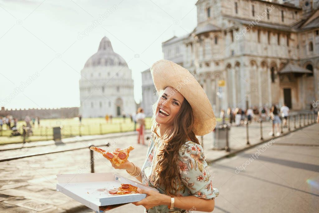 happy stylish woman in floral dress with pizza and hat near Duomo di Pisa.