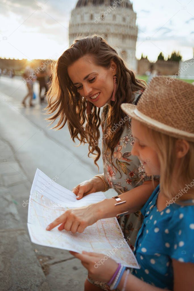 smiling modern mother and child with map in piazza dei miracoli in Pisa, Italy.
