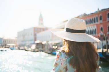 İtalya 'da Venedik seti üzerinde gezintiye çıkmış, çiçekli elbisesi olan şık, orta yaşlı bir gezgin kadın gördüm..
