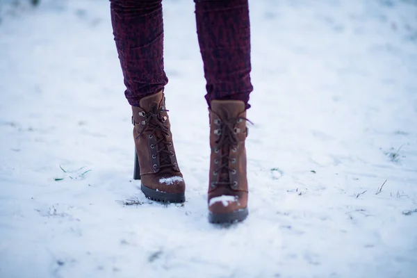 Mujer con botas negras de moda sobre nieve blanca de cerca piernas de mujer  con elegantes botas de cuero de invierno