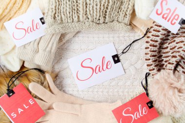 Kış dairesi eldivenler, şapkalar, kışlık giysiler ve beyaz örgü arka planda satış etiketi ile yatıyordu..