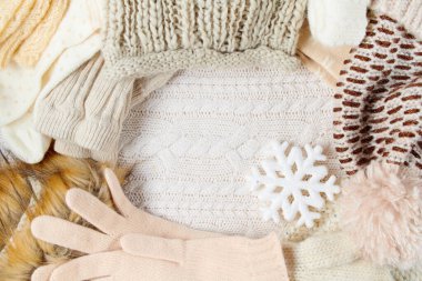 Kar taneleri, eldivenler, şapkalar ve beyaz örülü arka planda kışlık giysiler..