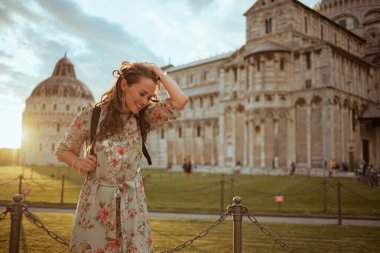 Sırt çantalı ve çiçekli zarif gezgin kadın Duomo di Pisa yakınlarında gezintiye çıkıyor..