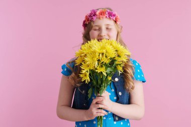 Sarı kasımpatı çiçekleri ve pembe üzerine izole edilmiş boho stili saç bandıyla gülen modern çocuk..