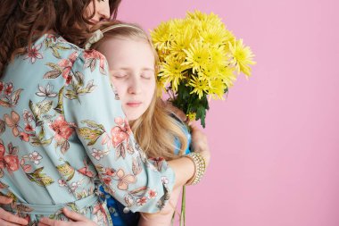 Uzun dalgalı saçlı, sarı kasımpatı çiçekli, pembe üzerine izole edilmiş duygusal bir anne ve çocuk..