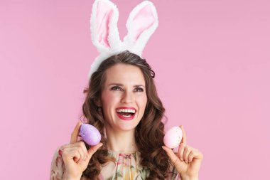 Çağdaş, orta yaşlı, çiçekli elbiseli, tavşan kulaklı ve pembe renkli paskalya yumurtası olan bir kadın..