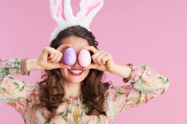 Zarif orta yaşlı kadın, uzun dalgalı esmer saçlı, tavşan kulaklı ve pembe üzerinde paskalya yumurtası olan..