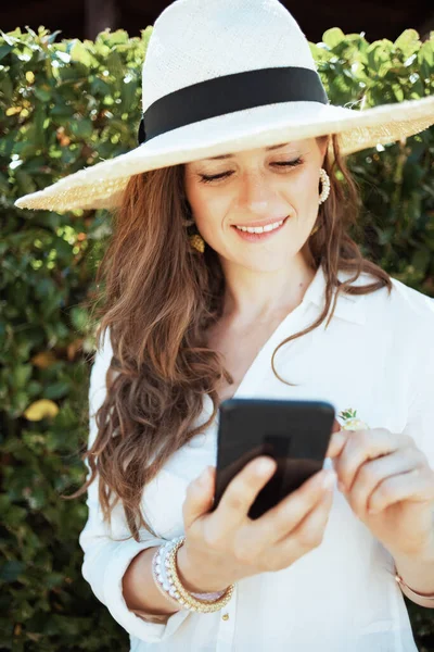 Mulher Moderna Duvidando Camisa Branca Com Chapéu Usando Aplicativo Smartphone — Fotografia de Stock