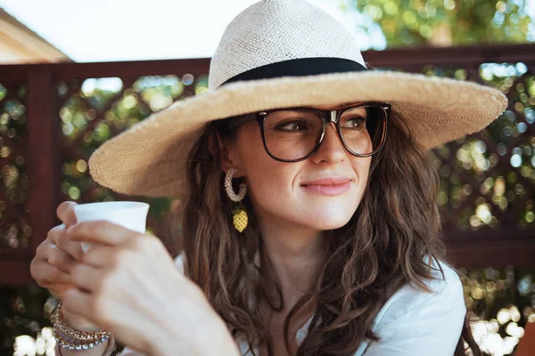 Zamyšlená Elegantní Fena Bílé Košili Šálkem Kávy Kloboukem Brýlemi Terase — Stock fotografie