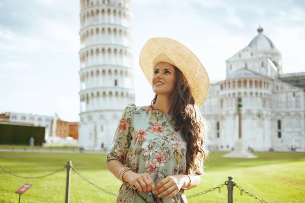 花のドレスを着た若い観光客の女性は イタリアのピサの斜塔の近くで遠足をしています — ストック写真