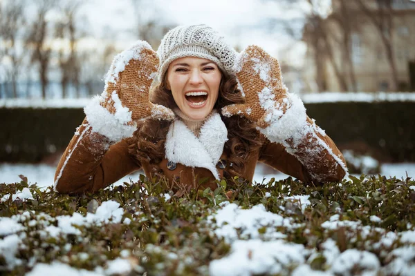 今年冬季 这位40岁的女士身穿针织的帽子和羊皮外套 头戴雪白的手套 站在城市公园外 她的形象是一个笑容可亲的40岁女人 — 图库照片