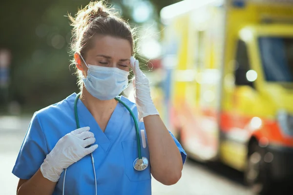 コロナウイルスのパンデミック 救急車の近くの聴診器や医療マスクを着た現代の救急隊員の女性を強調しました — ストック写真