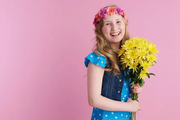 黄色の菊の花とピンクの背景に隔離されたBohoスタイルのヘアバンドと全体的に点線青でスタイリッシュな子供の肖像画 — ストック写真