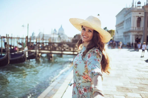 幸せな中年旅行者女性です花のドレスで帽子でヴェネツィア イタリアの堤防上の観光スポットを探索 — ストック写真