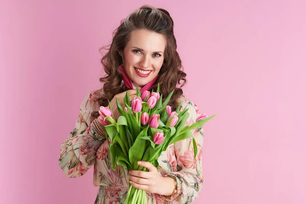 40歳の現代女性の花のドレスでチューリップの花束ピンクのマスクピンクの背景に隔離された — ストック写真