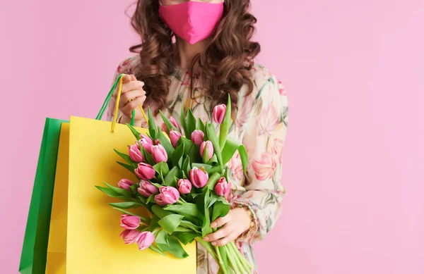 閉鎖上の女性とともに長い波状ブルネットの髪でチューリップ花束 ピンクマスクとショッピングバッグに対するピンクの背景 — ストック写真