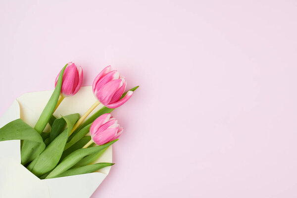 Весенняя плоская лежала с письмом и тюльпанами, изолированными от розового.