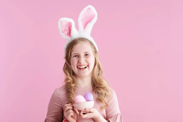 幸せな現代の子供の肖像画でピンクのドレスにウサギの耳とカップのイースターエッグにピンクの背景 — ストック写真