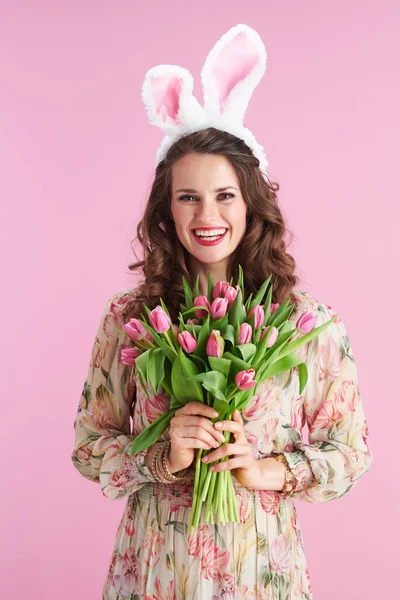 流行の女性とともに長い波状ブルネットの髪でチューリップ花束とウサギの耳ピンクの上に隔離 — ストック写真