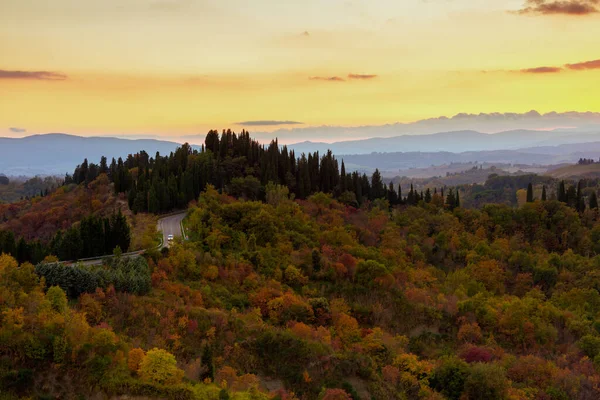 landscape with hills and road in Tuscany, Italy in autumn at sunset.