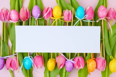 Kağıt çarşaf, lale ve pembe üzerine izole edilmiş paskalya yumurtalarıyla bezenmiş..