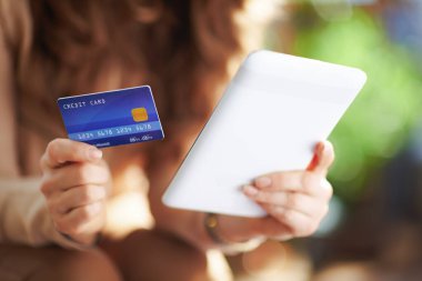 Yeşil Ev. Güneşli bir günde evde tablet tablet kullanan kredi kartı olan bir kadına yakın çekim..