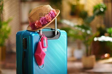 Coronavirus salgını sırasında seyahat et. Dezenfektanlı tekerlek çantası, tıbbi maske ve hasır şapka..