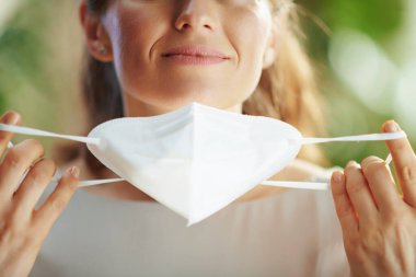 Covid-19 salgını. Orta yaşlı kadının ffp2 maskesini çıkarmasına yakın çekim..