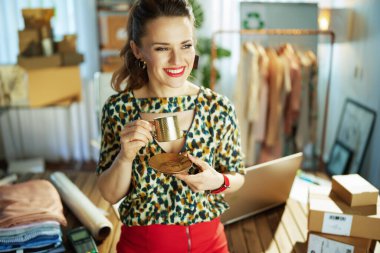 Gülümsüyor. 40 yaşında. Ofisinde bir fincan kahve olan küçük işletme sahibi bir kadın..