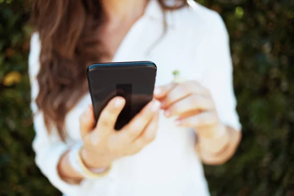 緑の壁の近くに屋外のスマートフォンアプリを使用して白いシャツの女性の閉鎖 — ストック写真