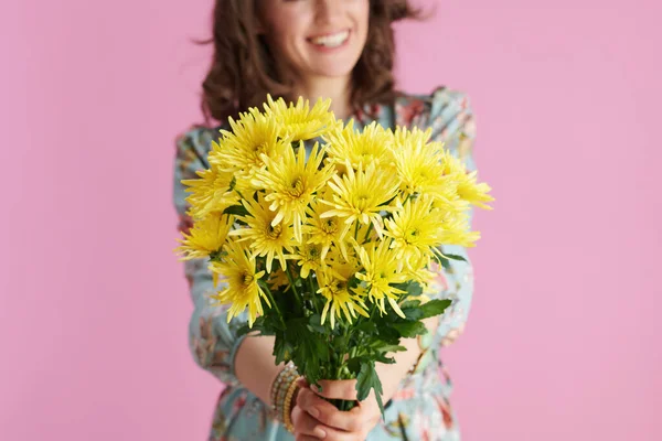 閉じる上の幸せな中年女性に長いです波状ブルネットの髪与えます黄色菊の花に対してピンクの背景 — ストック写真