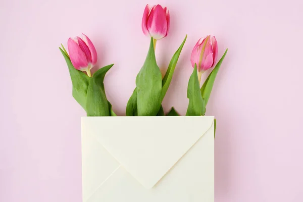 春のフラットレイにピンクで隔絶された手紙とチューリップ — ストック写真