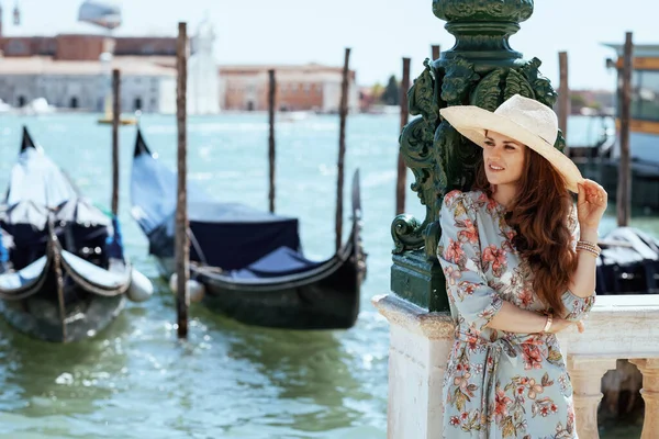 リラックスしたスタイリッシュな旅行者の女性の花のドレス帽子ヴェネツィア イタリアの堤防上の観光スポットを探索 — ストック写真