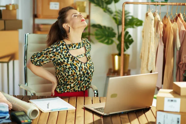疲惫优雅的中年小企业主女人 带着笔记本电脑 办公室里背痛 — 图库照片