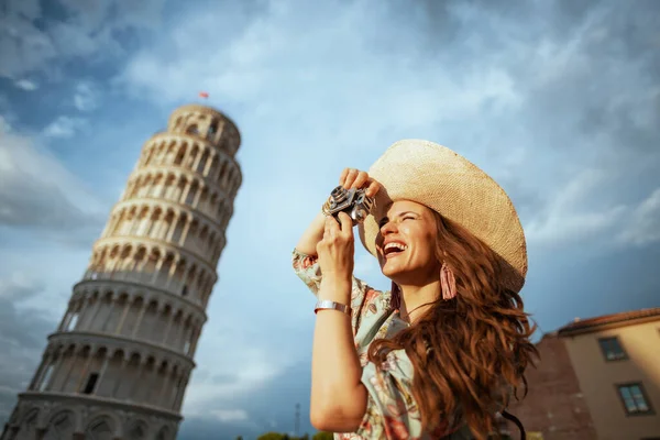 意大利比萨斜塔附近 身穿花衣 头戴复古相机 头戴礼帽的快乐的时尚旅游女性 — 图库照片